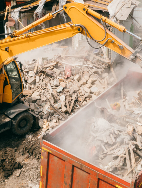 Excavator breaks building and loads construction waste into truck with its bucket. Demolition of building › RT Environnement Le Mans 72 Déconstruction et démolition