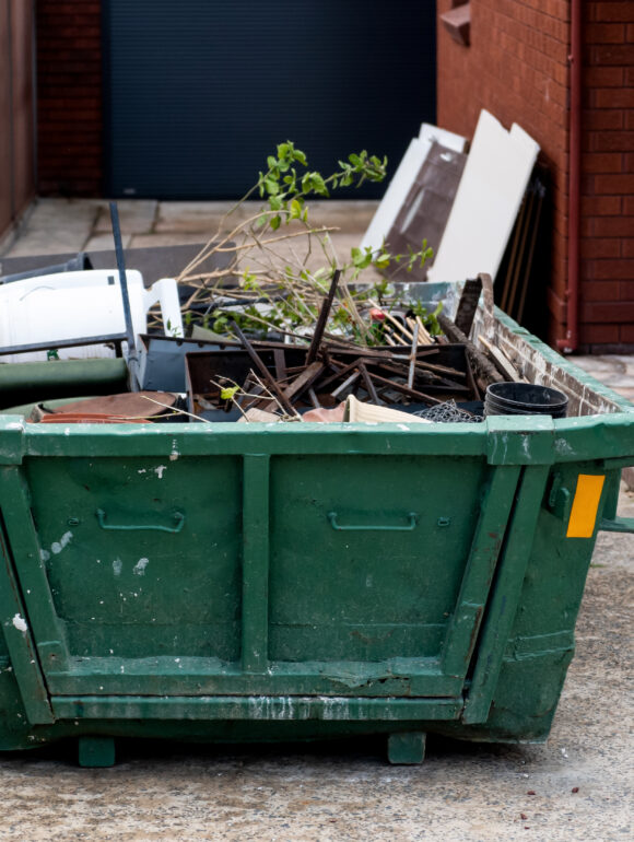 Skip bin with household waste rubbish on a front yard. House clean up concept. › RT Environnement Le Mans 72 Benne pour déchet